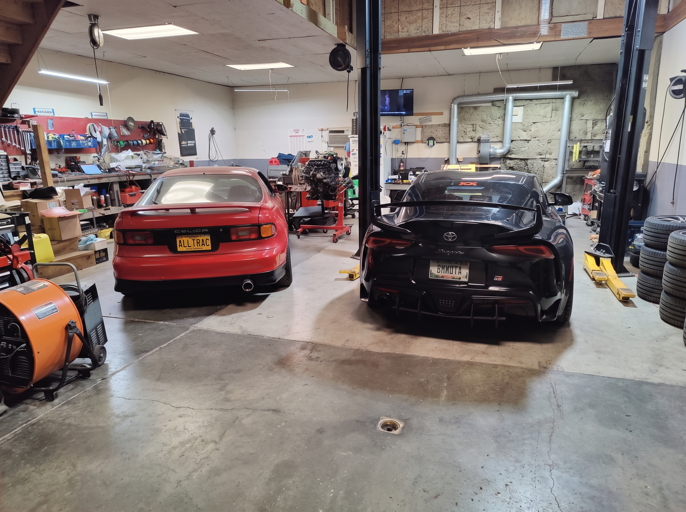 Red Toyota Celica All-Trac and black Toyota GR Supra parked in the shop