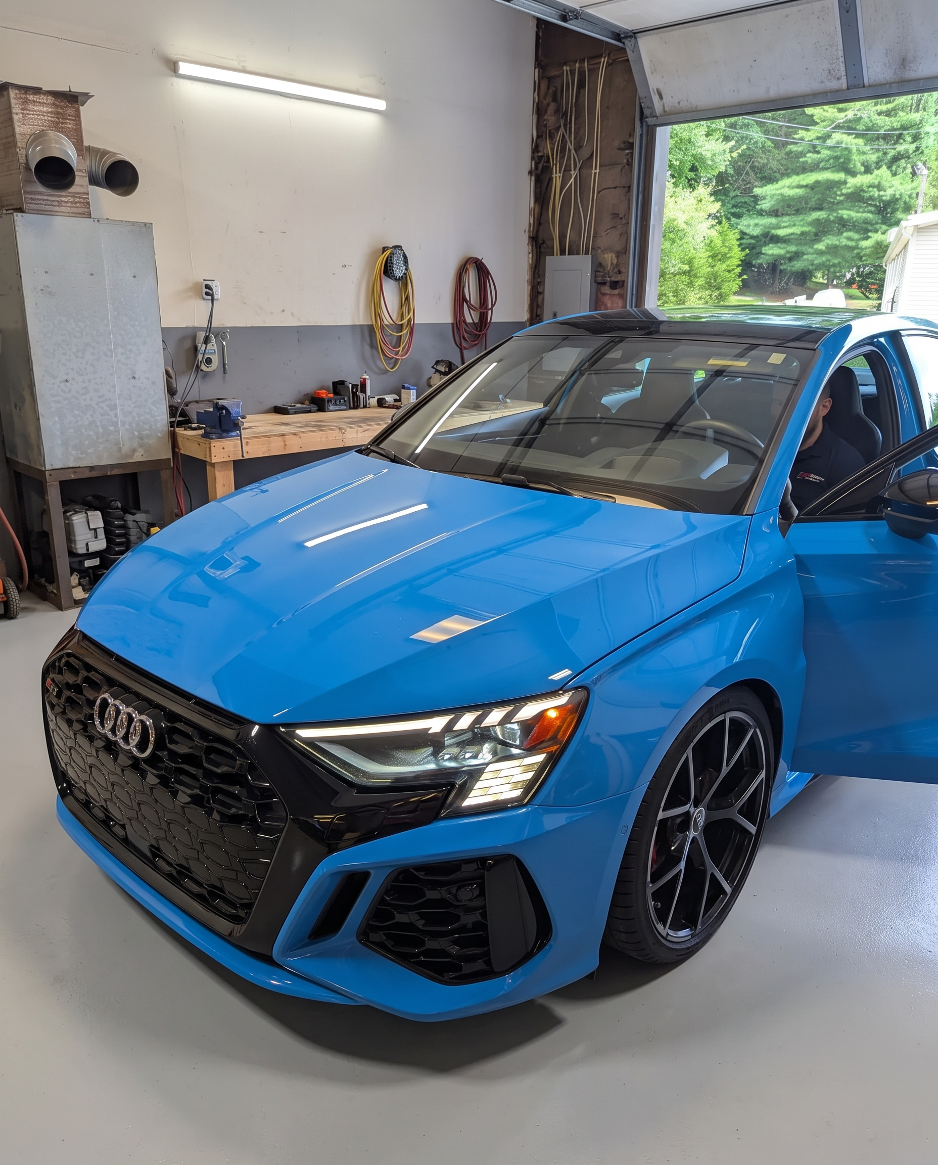 Blue Audi RS3 in the shop bay with the door open during a tuning session