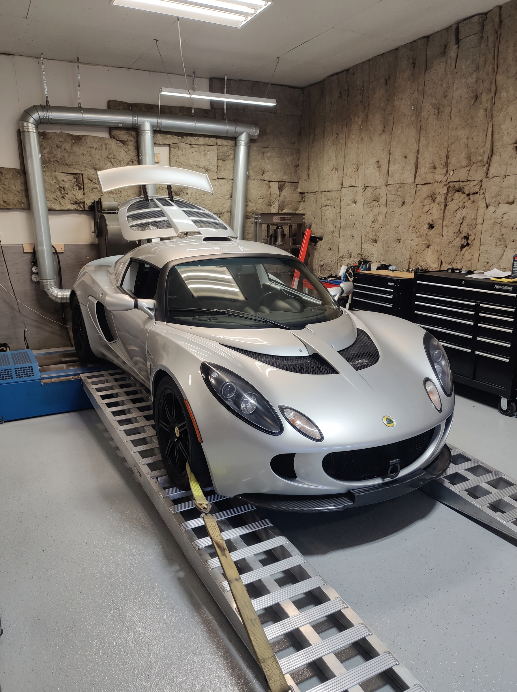 Silver Lotus Exige with rear wing strapped down on the dyno